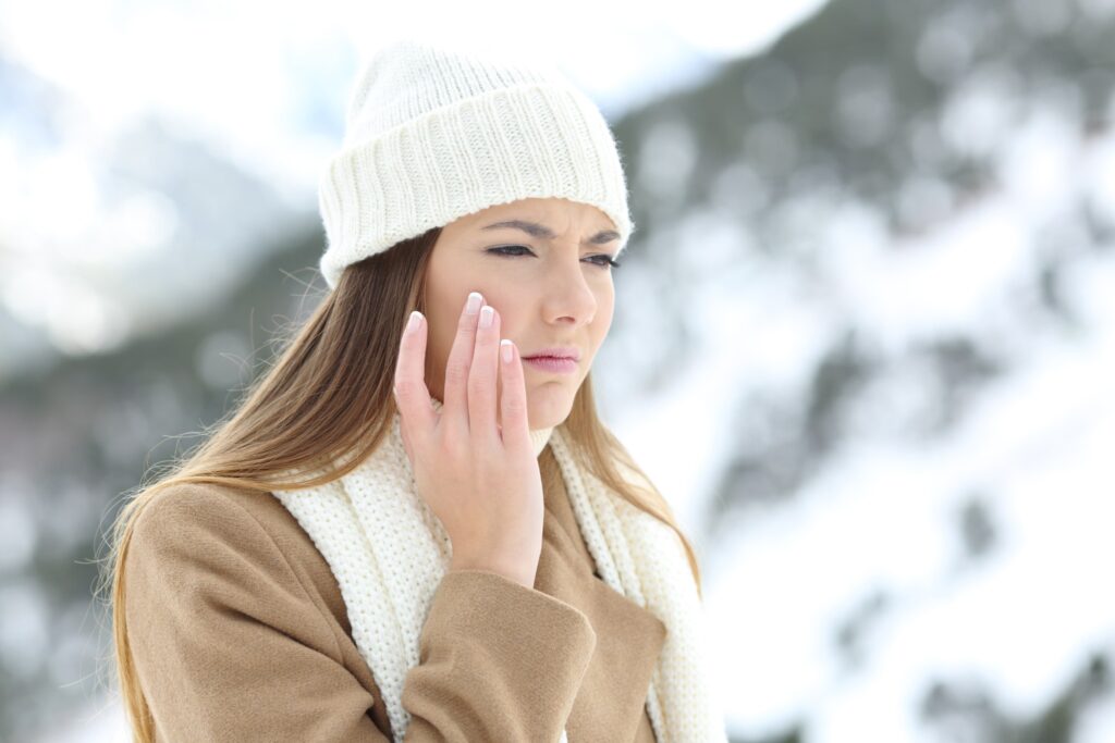 Knowing How To Care For Your Skin In The Winter Can Include Changing Your Products. Image Of A Woman Bundled Up In The Cold Weather, Feeling Her Dry Skin.