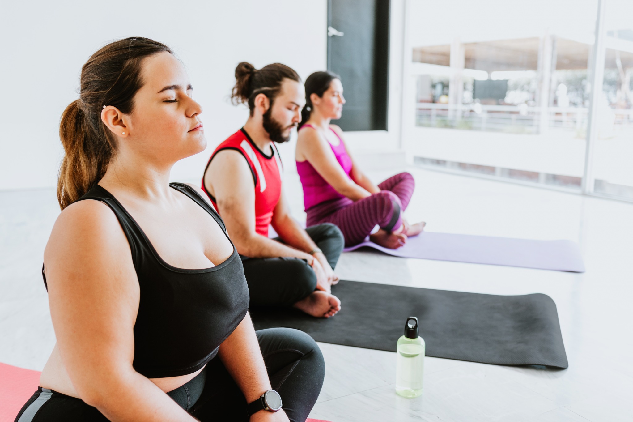 Image of two women and one man in a yoga class.