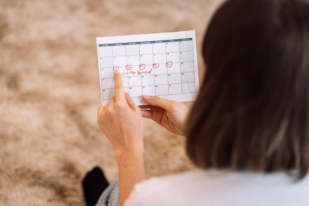 Yoga Supports Your Health Goals, Including Helping To Balance Your Hormones.  Image Of Woman Holding A Calendar To Track Her Menstrual Cycle.