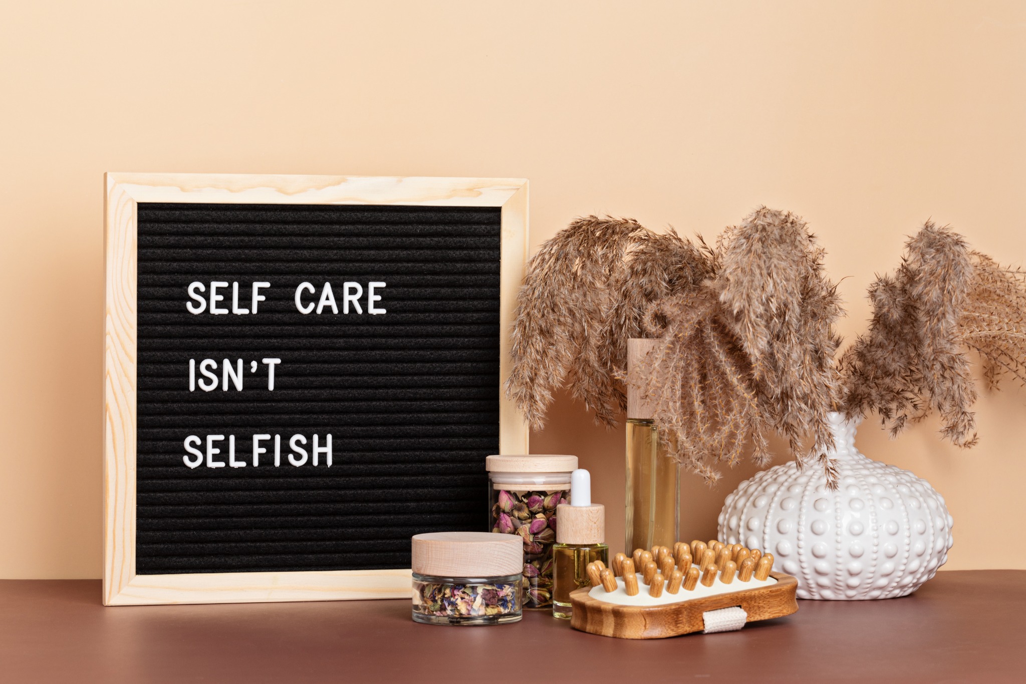 Image of self-care items next to a felt sign with the words "self-care isn't selfish"