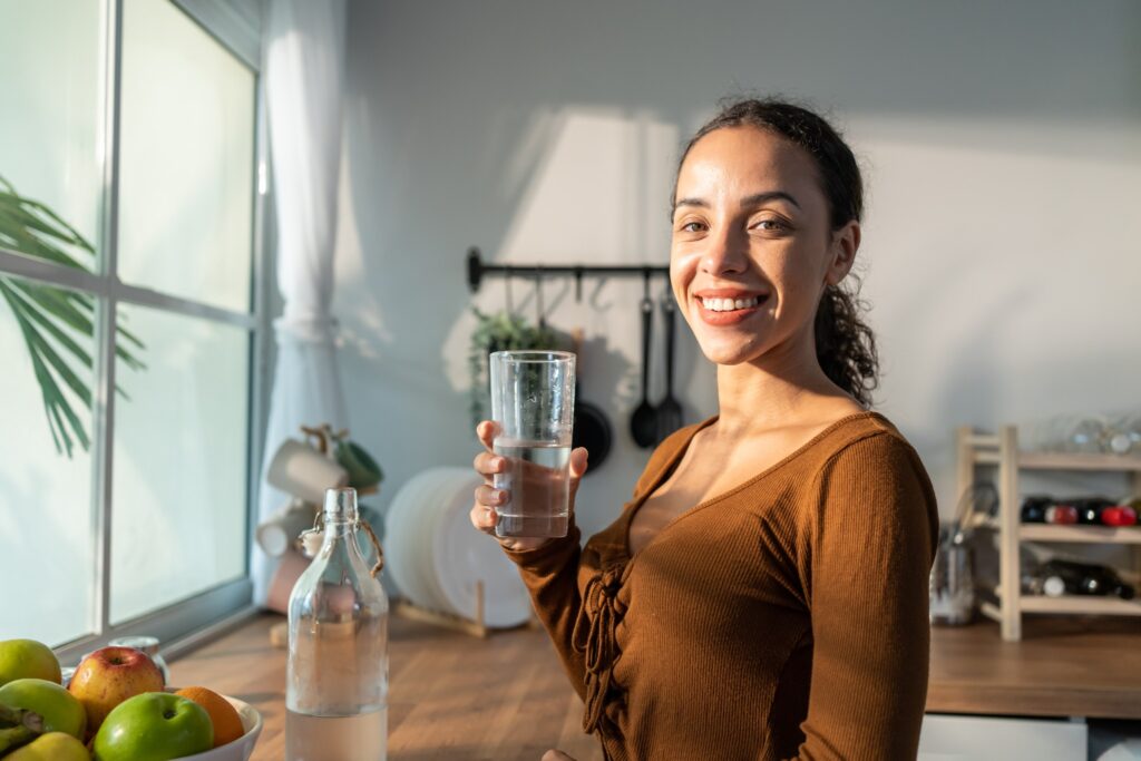 Image Of Woman In Her Kitchen Drinking A Glass Of Water.